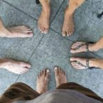 Looking down at 4 pairs of barefeet (mostly) pointing to the center of the photo